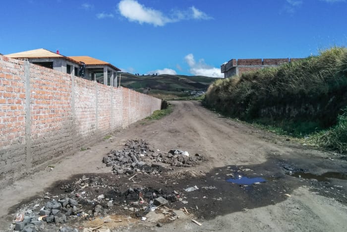 Dirt road with long brick wall in the rural landscape