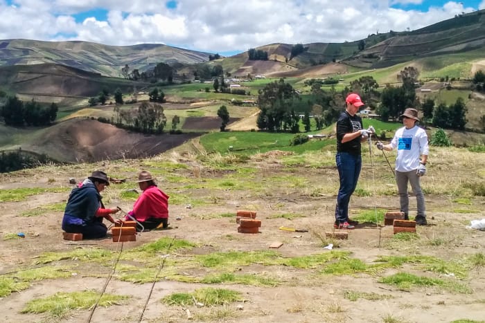 People cutting steel rebar in a grassy field