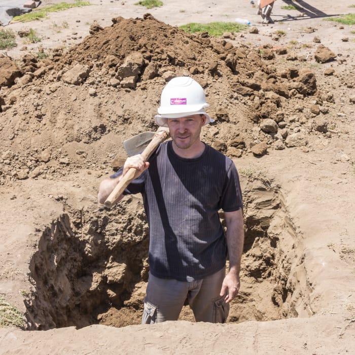 Person with pickaxe standing in hole in ground