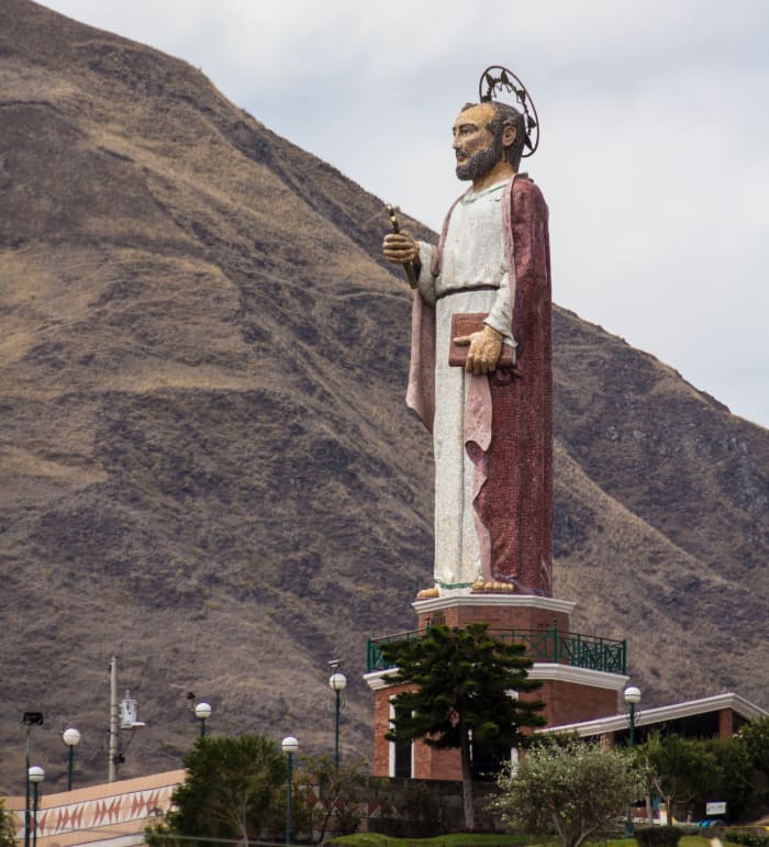 Large San Pedro statue overlooking the town of Alausí, with large hills in the background