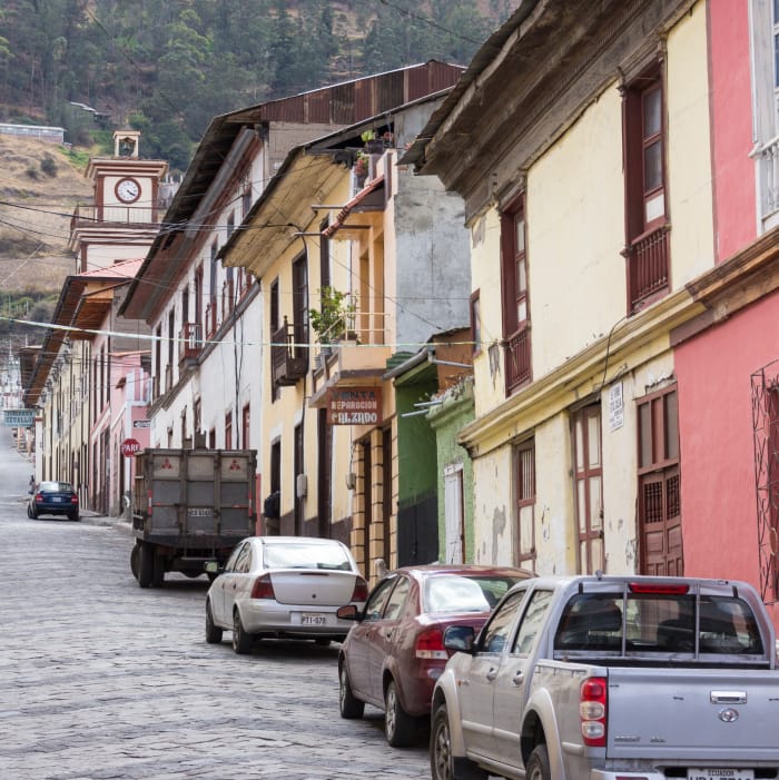 Cars parked on a steep cobblestone road leading up the hillside