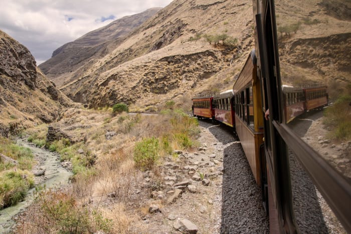 Train on tracks at the bottom of the valley, with mountains in the distance