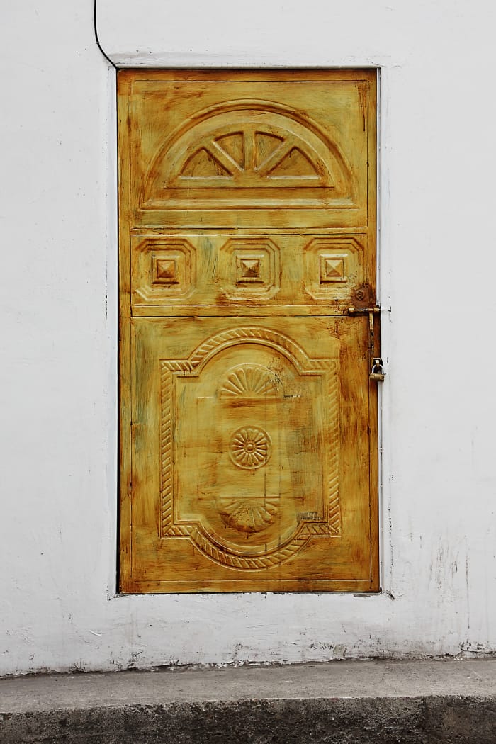 Gold or yellow carved door inset in a white stucco wall