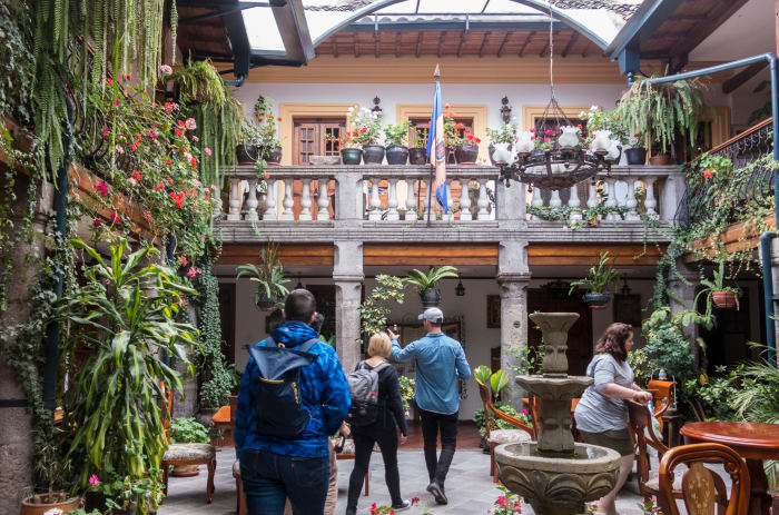 People in lush hotel lobby courtyard with vegetation