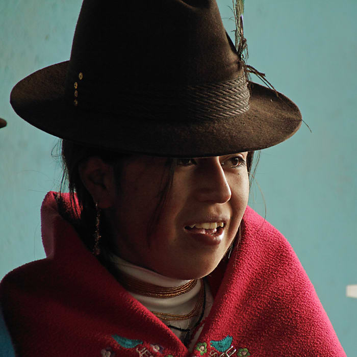 Indigenous girl smiling, wearing hat and red poncho