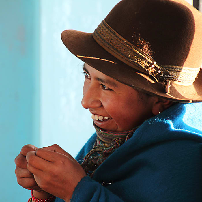 Indigenous girl smiling, wearing hat and blue poncho