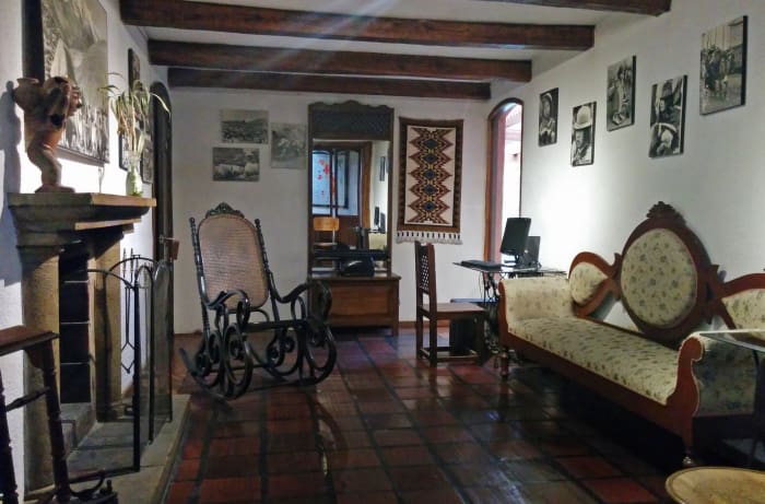 Small hotel lounge room with antique furniture, couch, rocking chair and fireplace