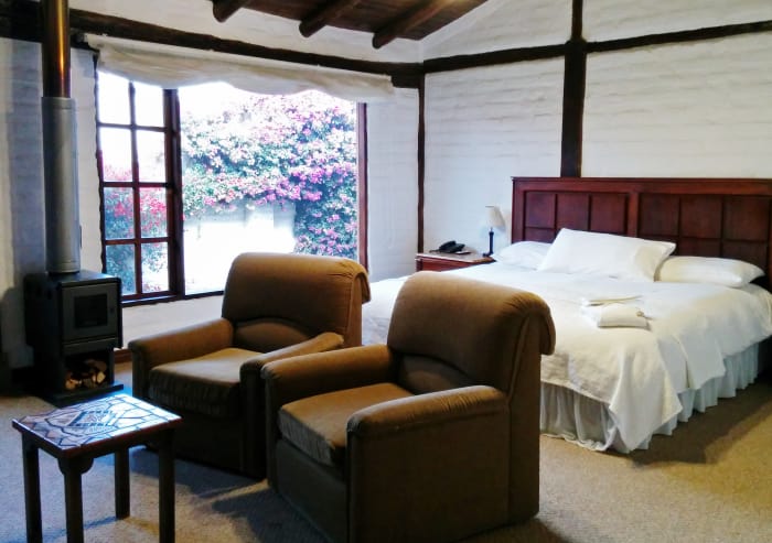 Hotel room interior with large window, fireplace, chairs and bed