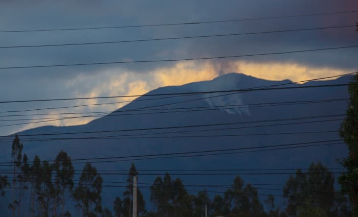 Mount Chimborazo in the distance with dark clouds, behind a group of power lines