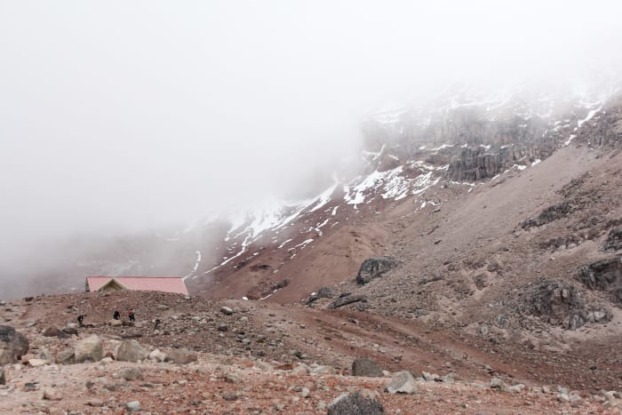 Refugio Whymper cabin roof below misty clouds against the mountain