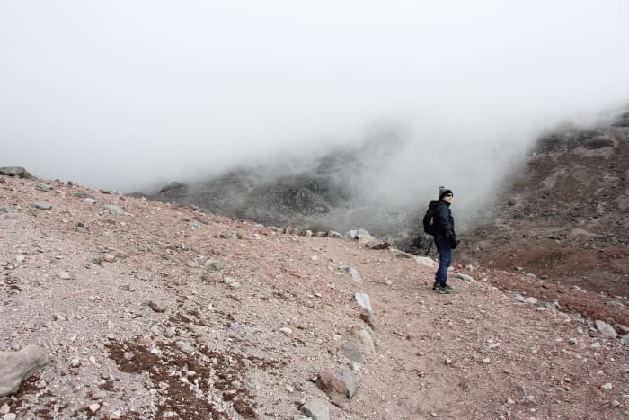 Person standing on hiking trail on mountain side