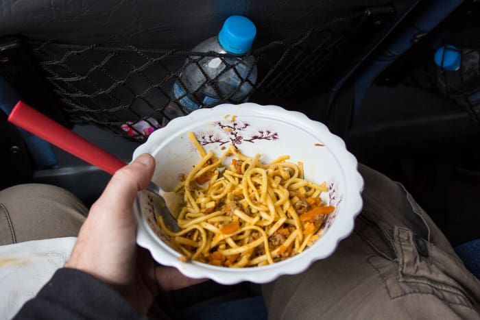 Eating a bowl of pasta noodles in the car