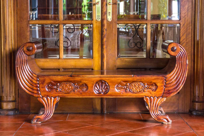 Ornate carved wood bench in front of glass doors