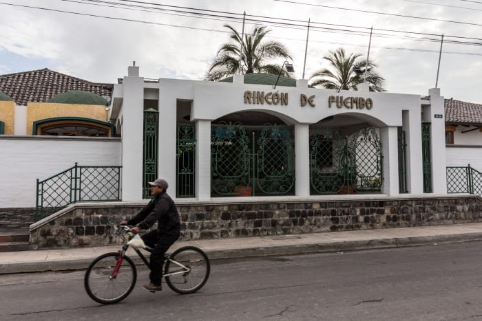 Man rides bicycle in front of hotel entry facade