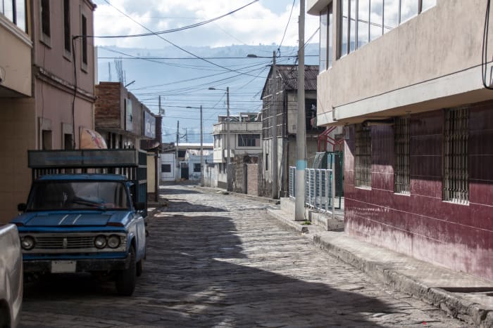 Empty cobblestone street with blue truck and red tile wall