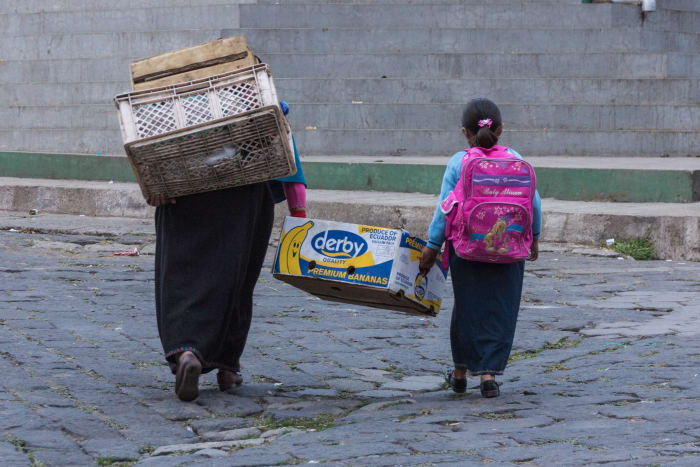 Mother and daughter carrying box of bananas