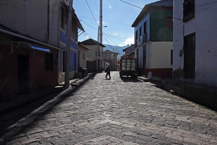 Man crosses empty cobblestone street